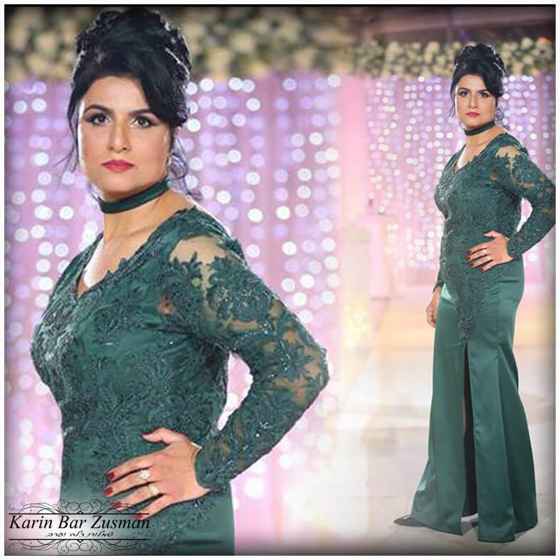 אישה בשמלת תחרה ירוקה עם תסרוקת אסוף וצ'וקר, פוזת עם יד על הירך, על רקע בהיר מטושטש.