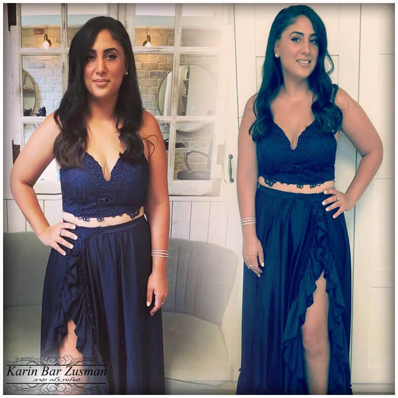 אישה בשמלה כחולה כהה עם חולצת קרופ-טופ תחרה, עומדת בבית עם יד על מותנה, מחייכת.