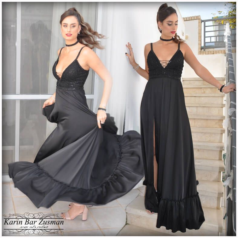 אישה בשמלה שחורה רשמי, מצטלמת על מדרגות, עם חצאית זורמת ומחוך תחרה.