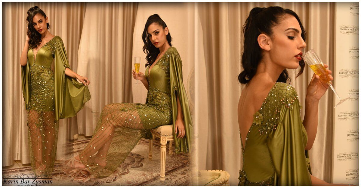 אישה בשמלה ירוקה לוגמת שמפניה, מצטלמת בסביבה אלגנטית עם וילונות עטופים.