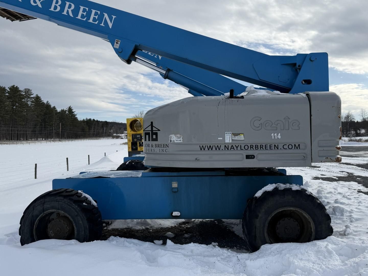 Blue Genie boom lift in snow, outdoors.