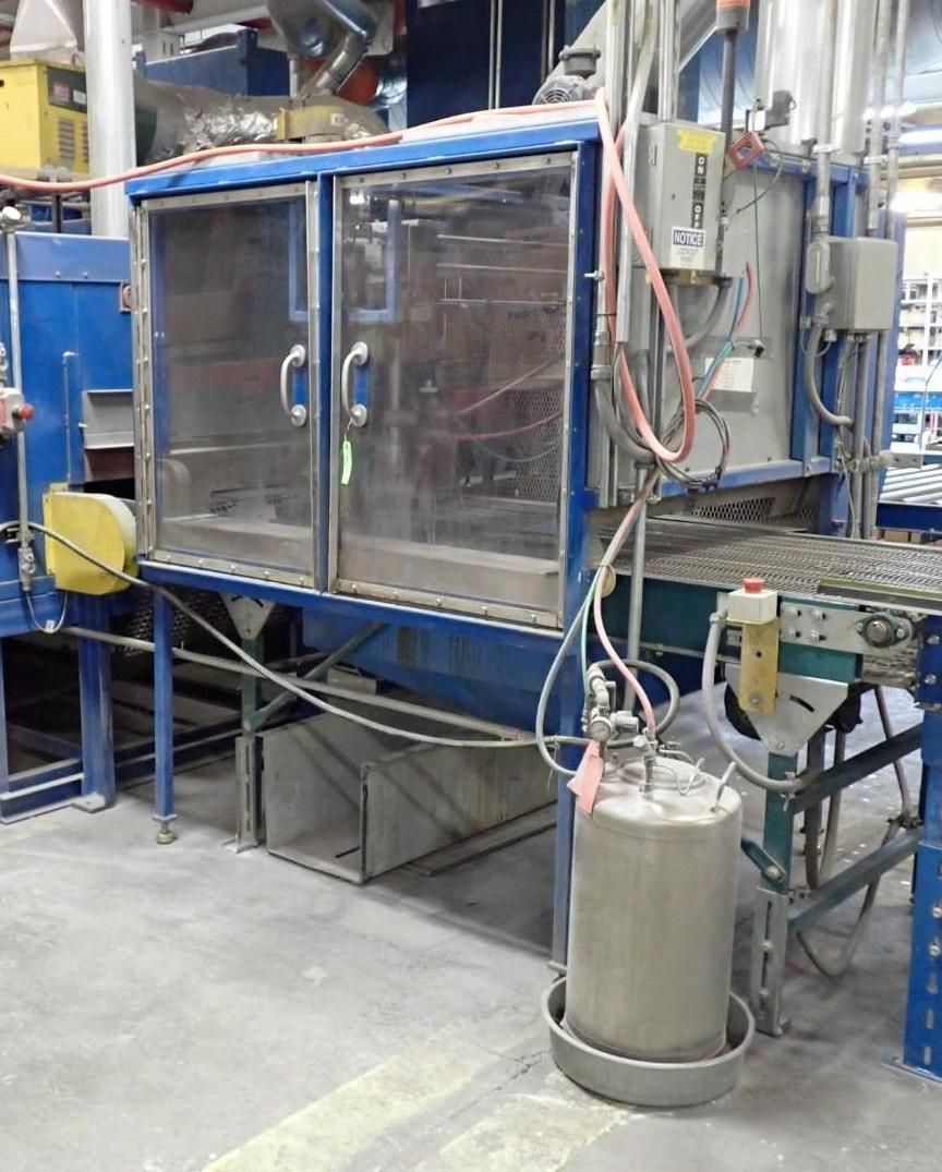 Blue industrial machine with glass doors and a tank connected to a conveyor belt.