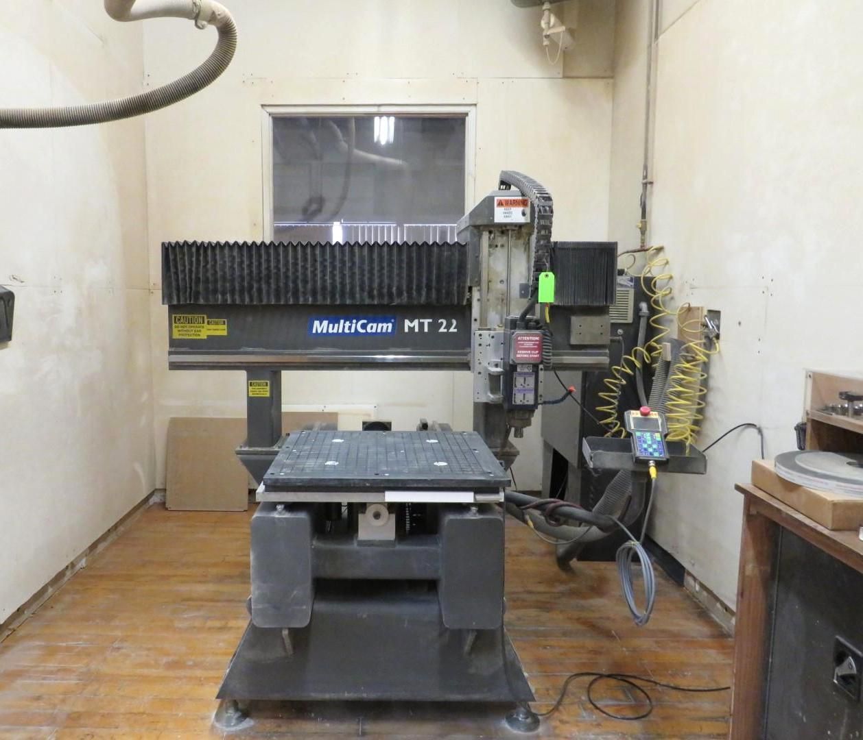 CNC machine, MultiCam MT 31, in a workshop. Gray machine, dark background, wooden floor.