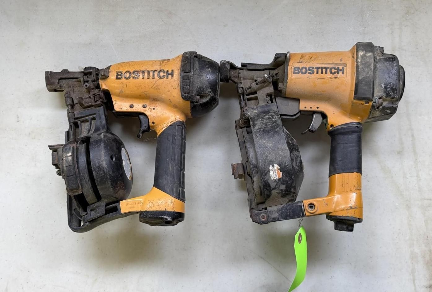 Two yellow and black Bostitch nail guns on a white surface.