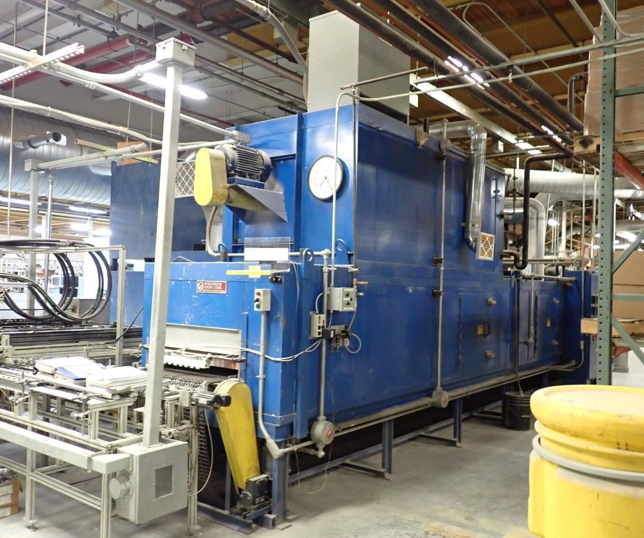 Blue industrial oven in a factory setting, with attached machinery.
