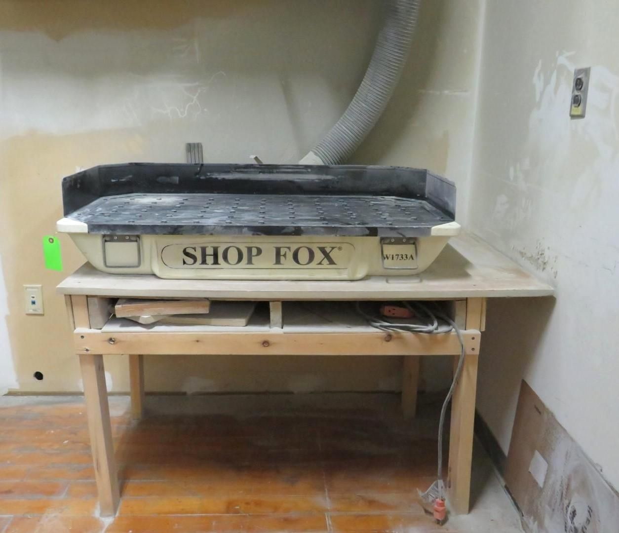 Shop Fox tile saw on a wooden table in a work area.