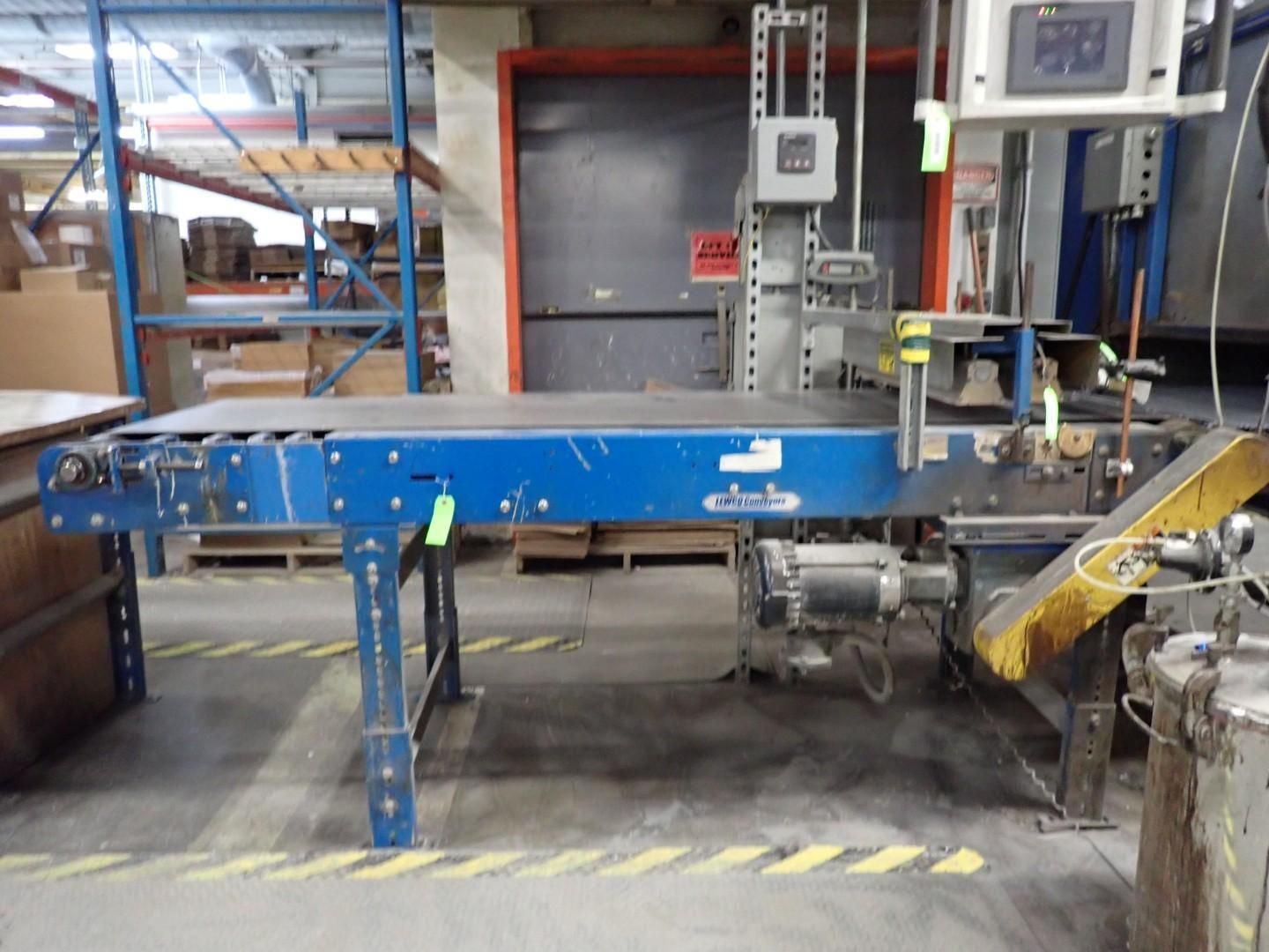Blue conveyor belt in a warehouse setting, with machinery and shelving visible.
