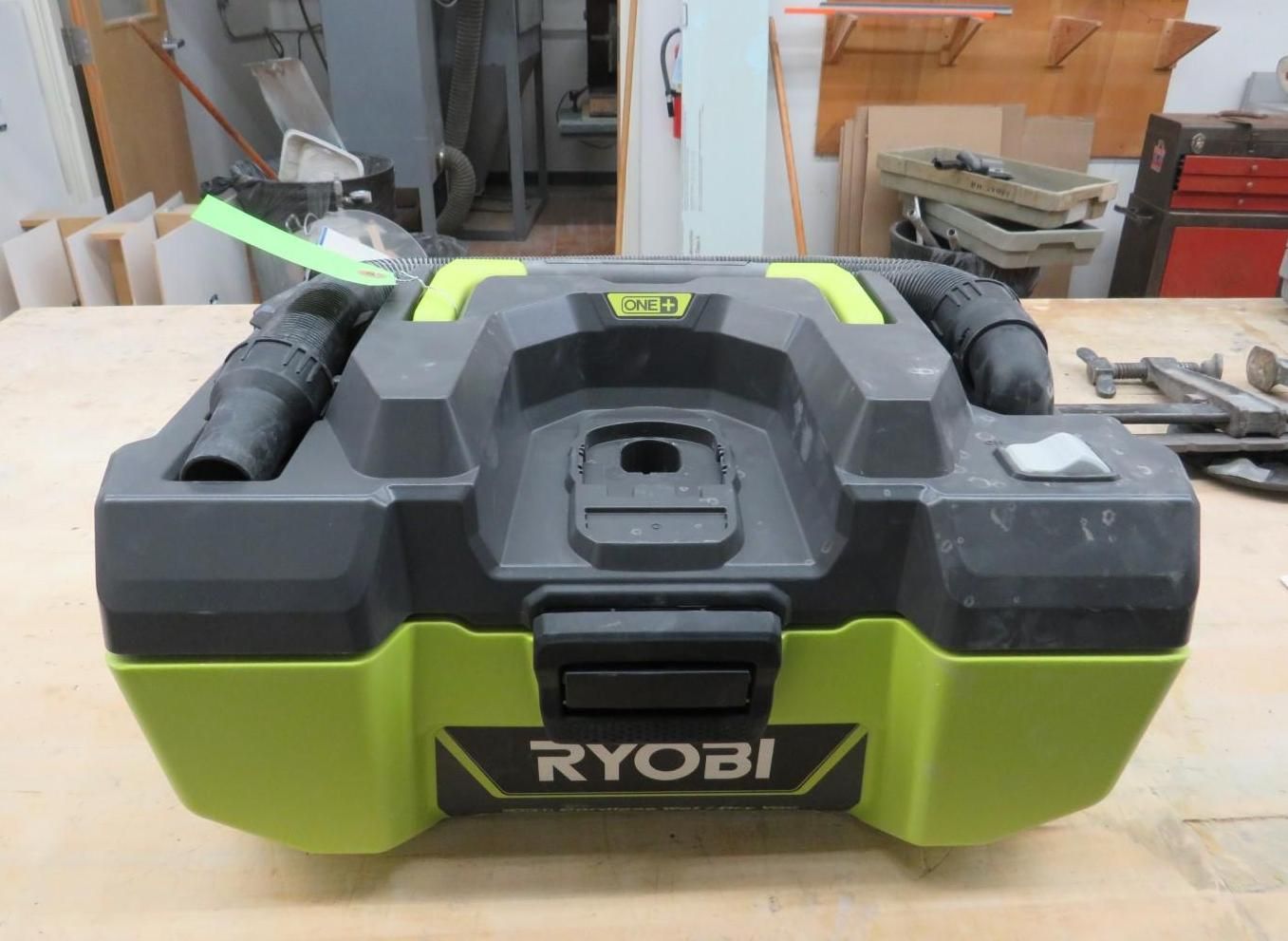 RYOBI cordless wet/dry vacuum, black and green, on a wooden surface.