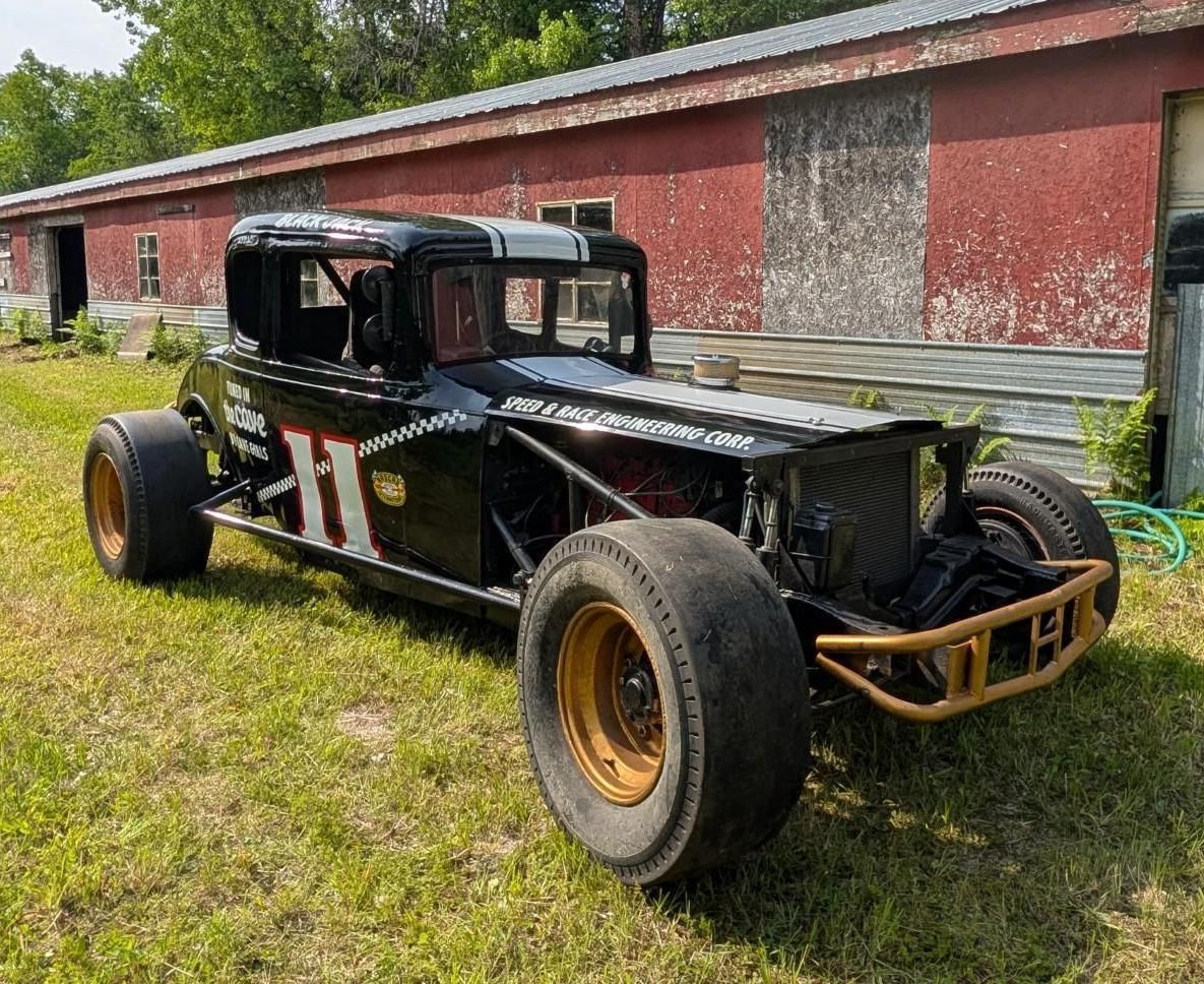 Black vintage hot rod parked on grass