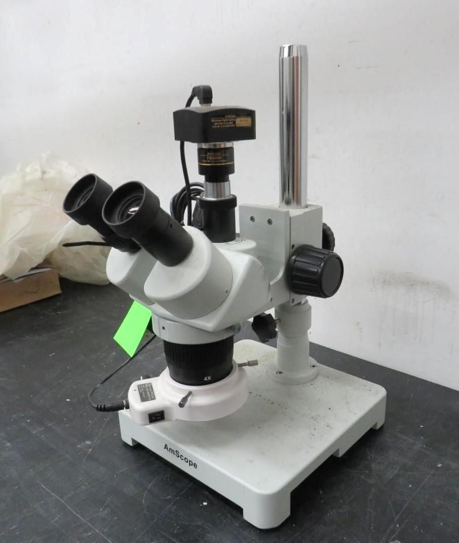 Stereo microscope with camera attached, white and black, on a white base.