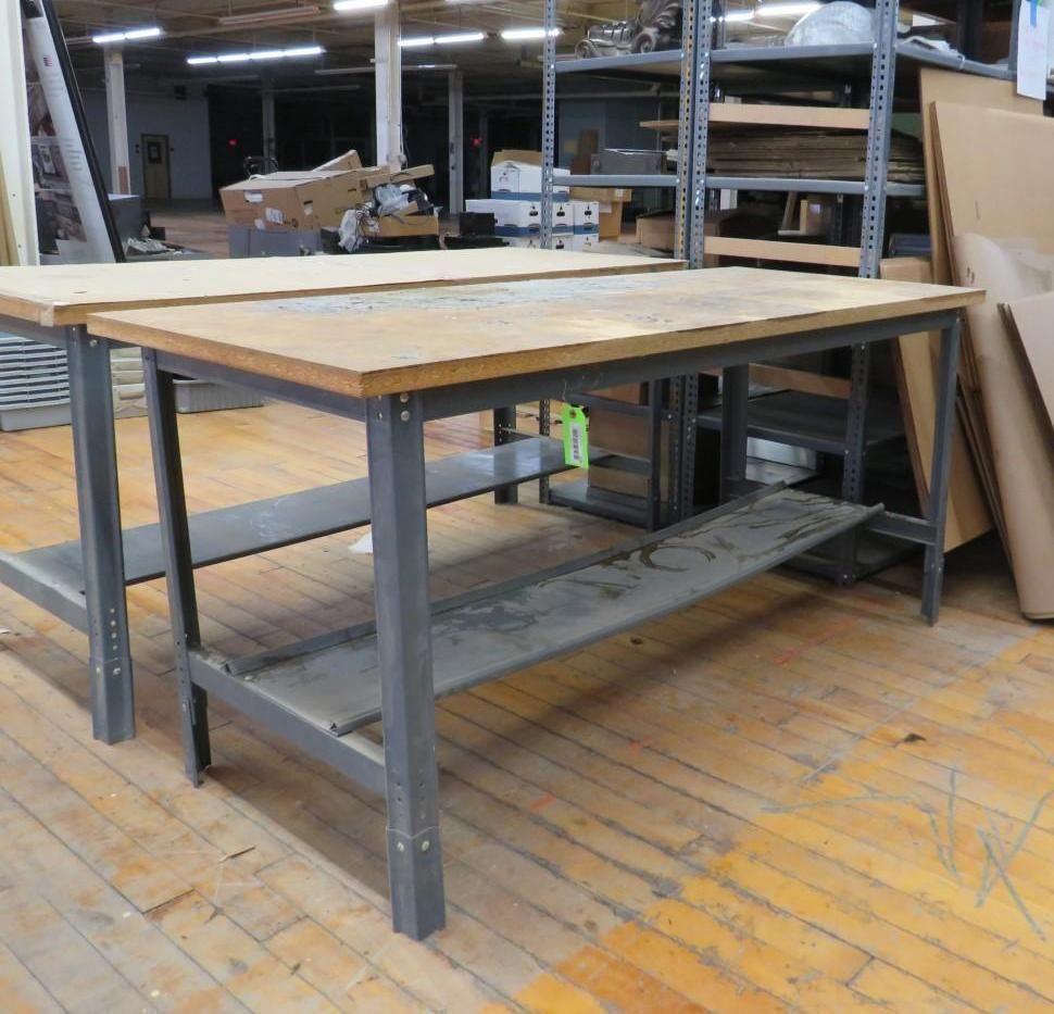 Two workbenches with metal frames and wooden tops in a warehouse.