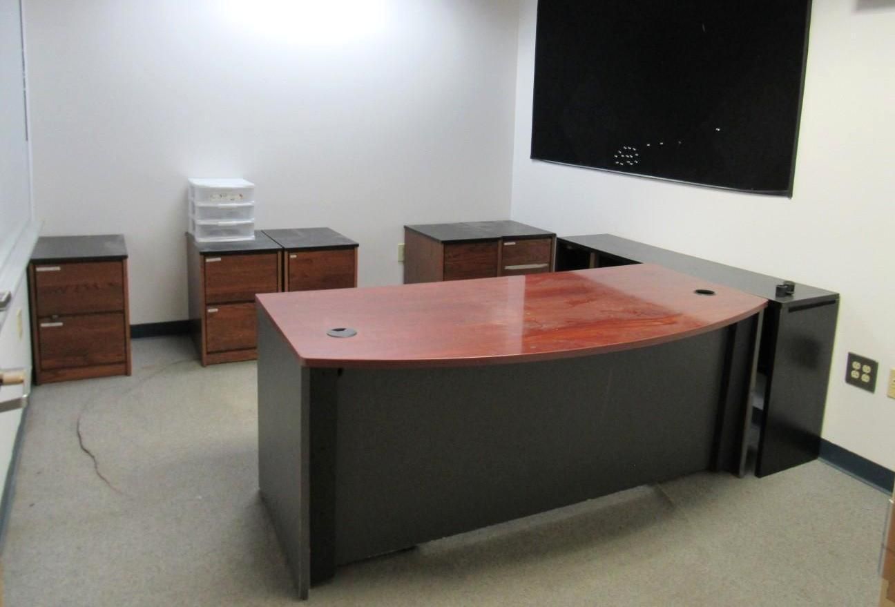 Office with a U-shaped desk, several filing cabinets, and a window with a dark covering.