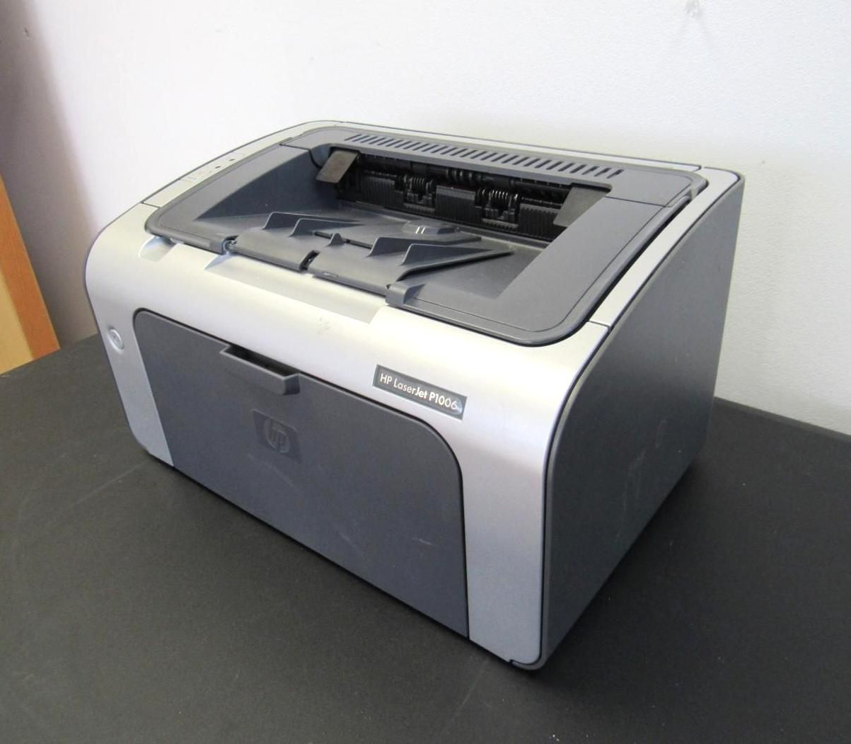 HP LaserJet P1005 printer, gray and black, sitting on a dark surface.