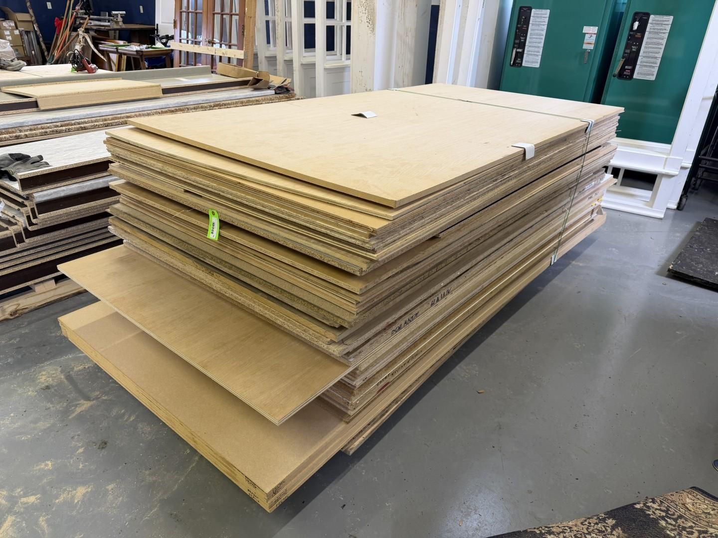Stack of brown corrugated cardboard sheets and other light-brown boards in an indoor setting.