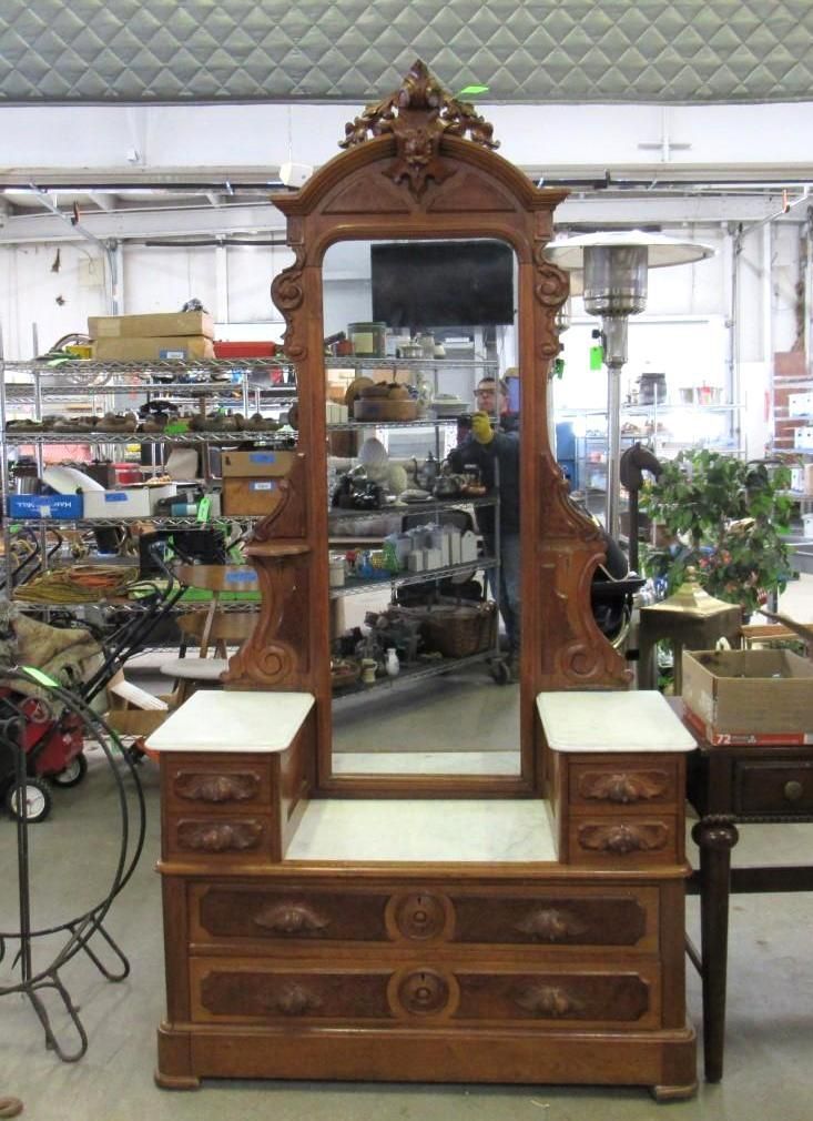 Ornate wooden vanity with marble top, mirror, and drawers; indoors.