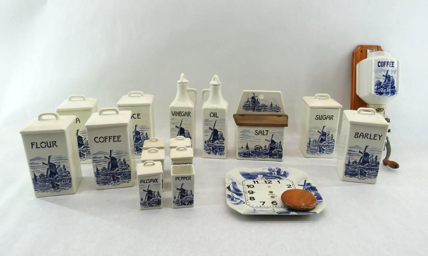 Collection of blue and white Dutch-style kitchenware, including canisters, oil bottles, and a wall-mounted grinder.