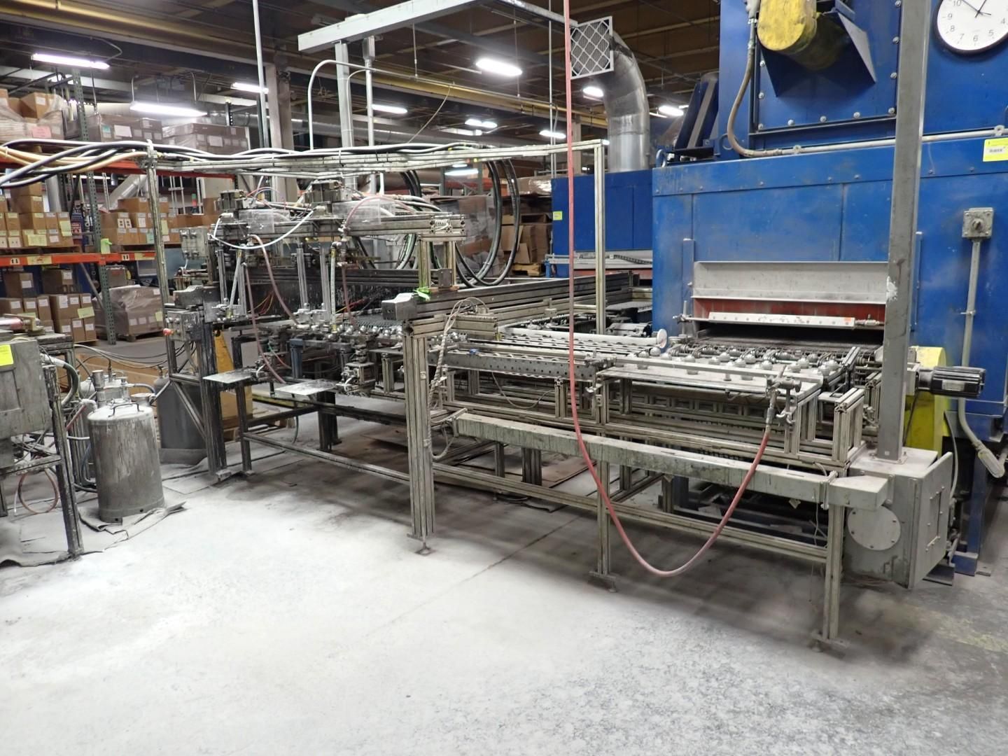 Factory machine, industrial setting. Gray metal machinery on concrete floor, blue oven, overhead lighting.