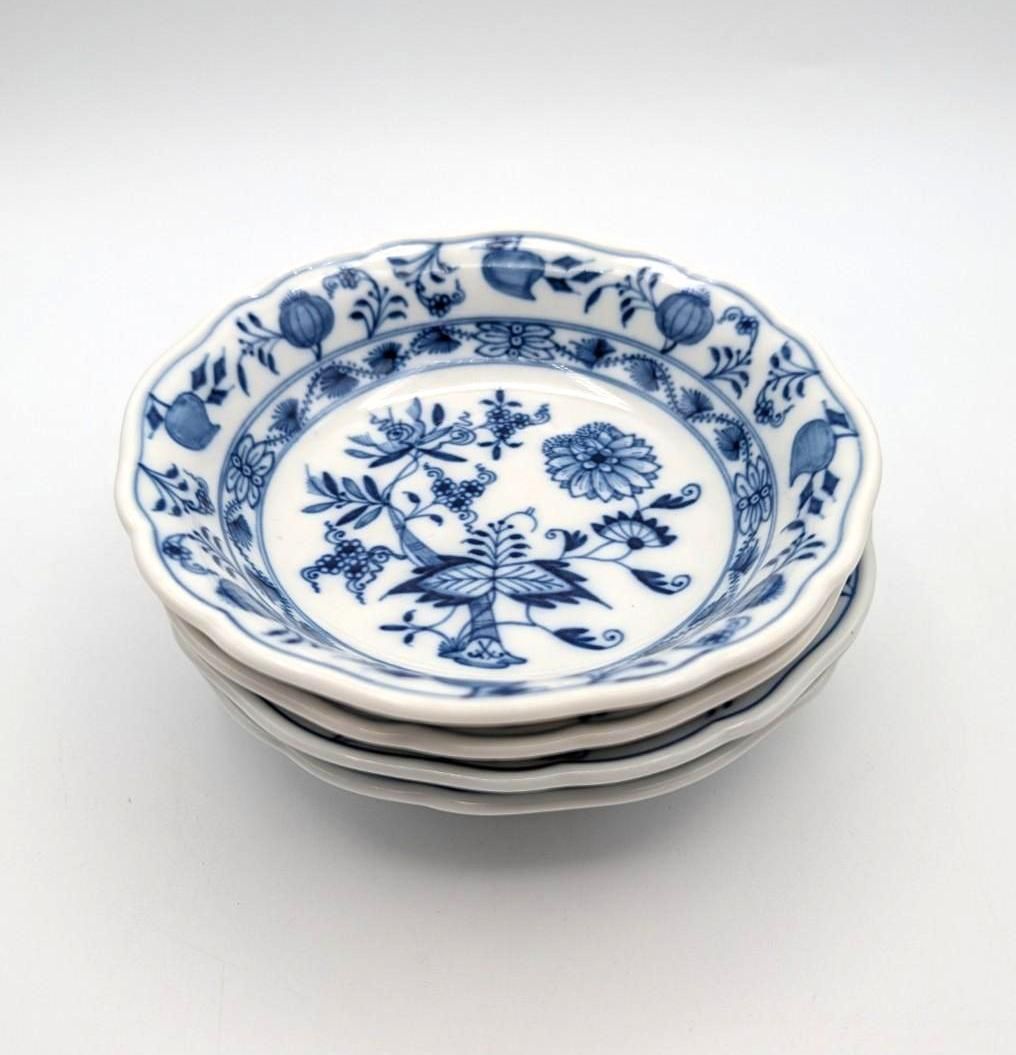 A small stack of three white porcelain bowls with a blue floral 
