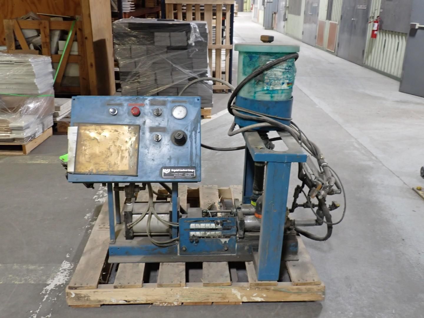 Blue industrial machine on a wooden pallet, with control panel, reservoir, and hoses in a warehouse.