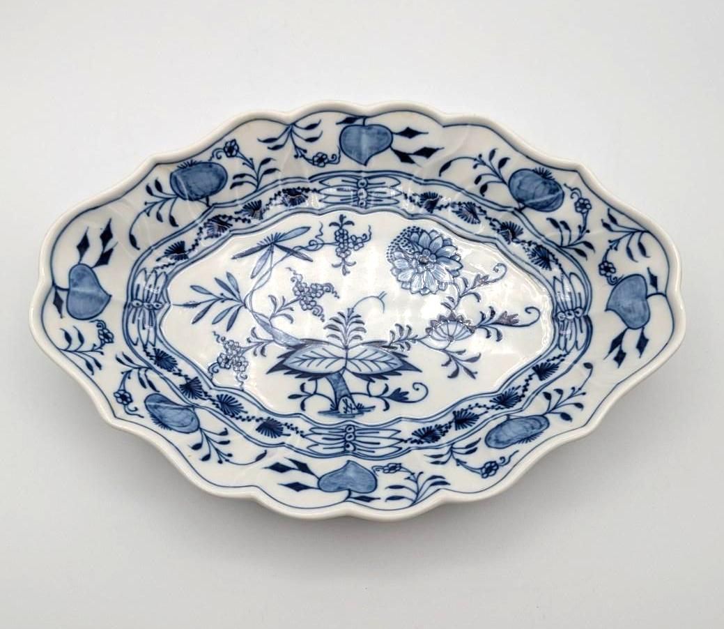 An oval porcelain dish with a scalloped edge, decorated with blue floral patterns and a lattice border on a white ground.