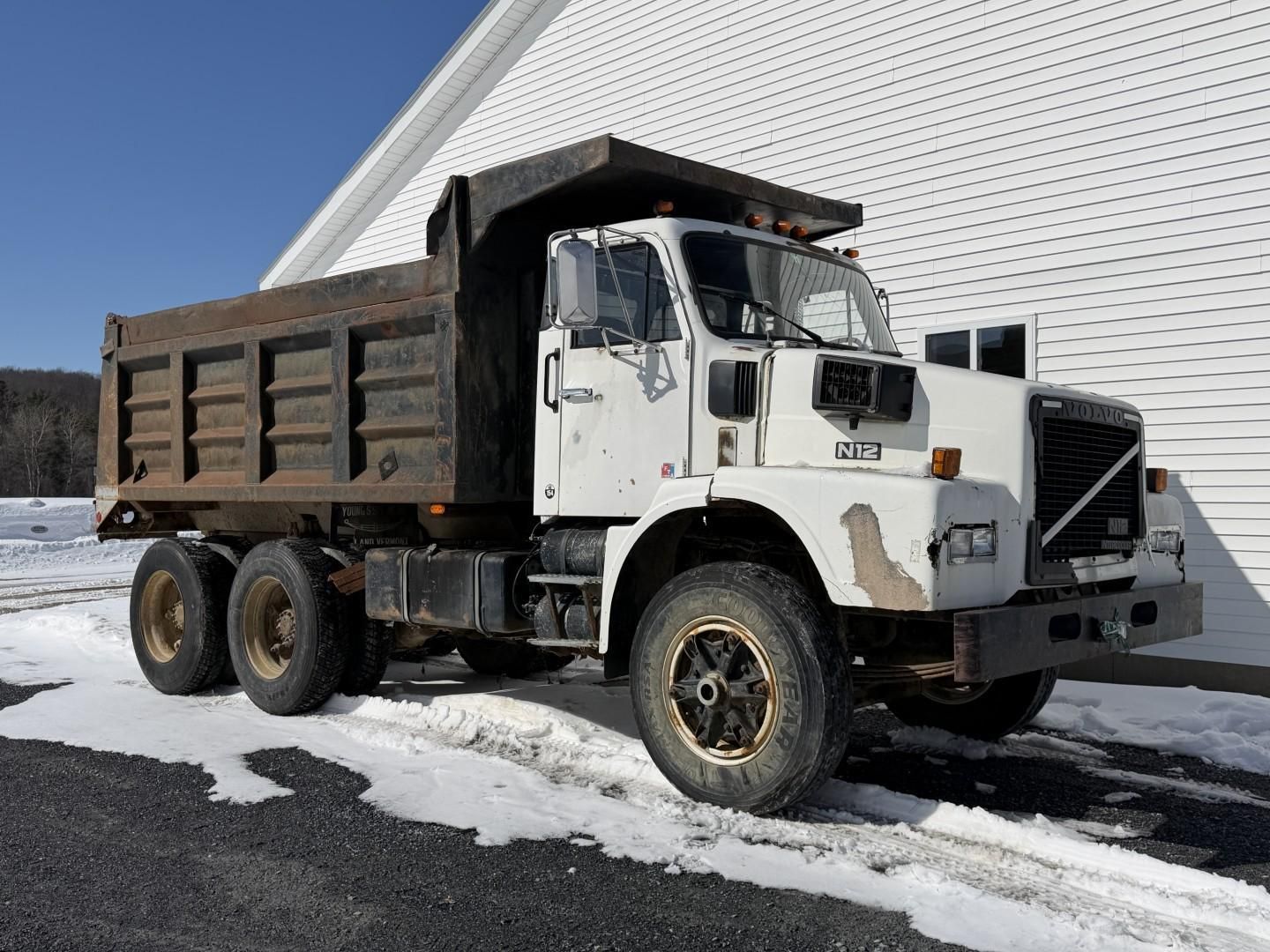 White Volvo dump truck parked on snow.