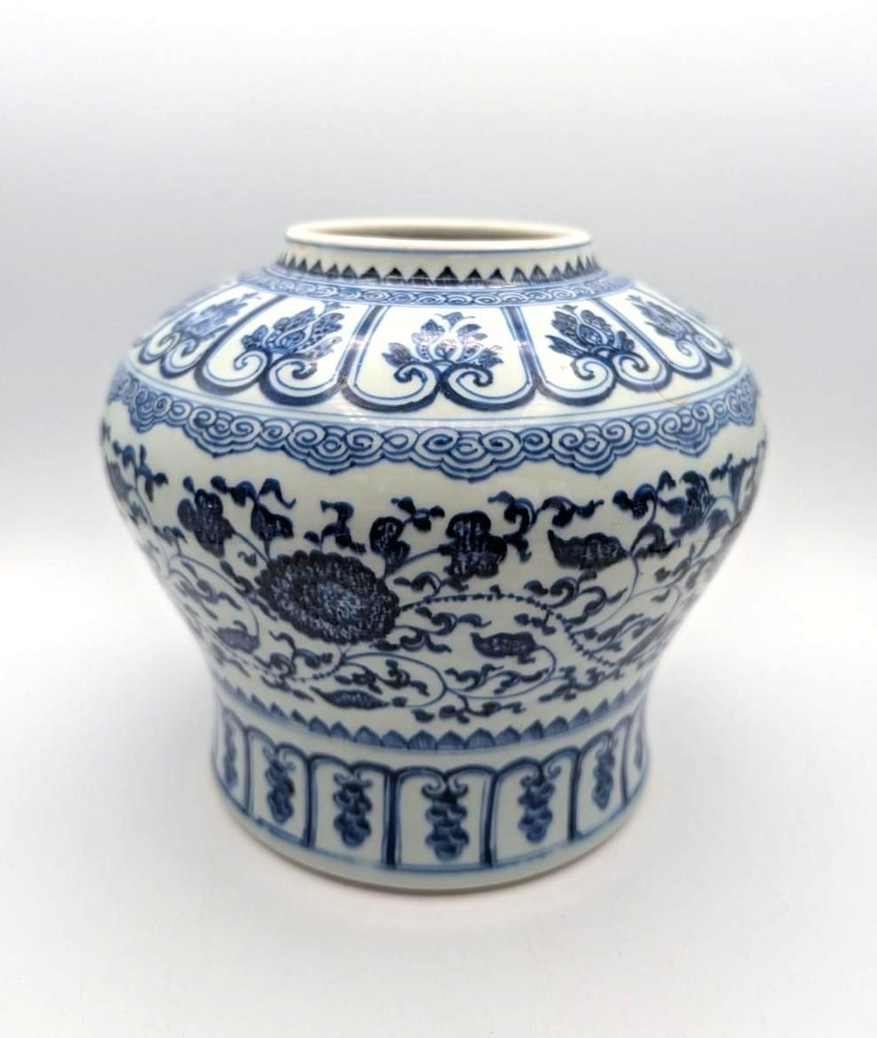 A blue and white porcelain jar decorated with floral patterns and geometric bands, set against a plain white background.