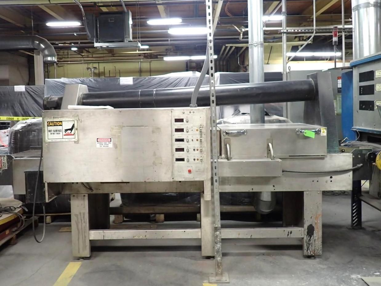 Stainless steel industrial machine in a warehouse setting.