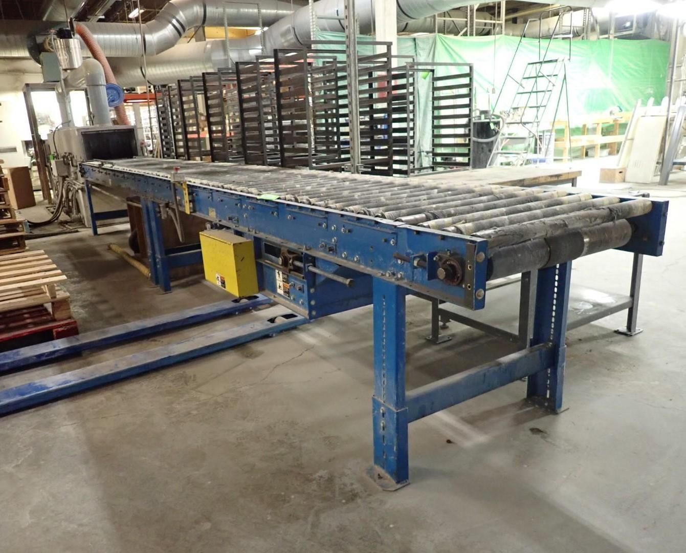 Blue conveyor belt with rollers in a factory setting.