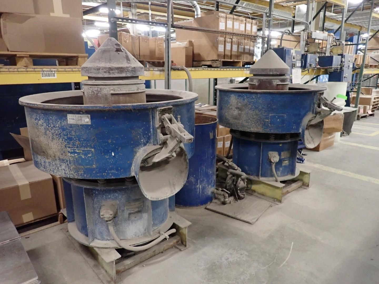 Two blue industrial vibratory finishing machines in a warehouse.