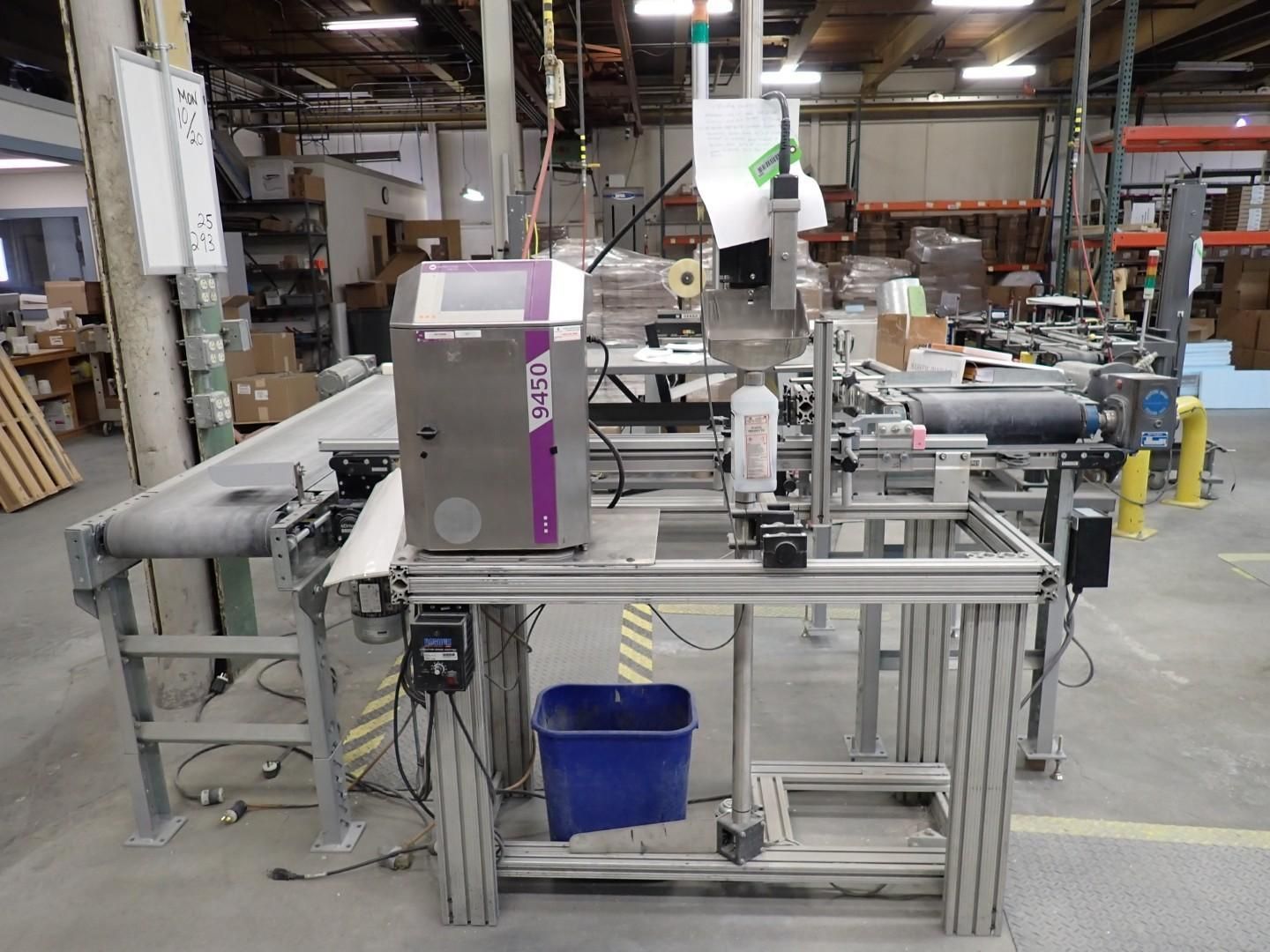 Industrial inkjet printer with conveyor belt in a warehouse setting.