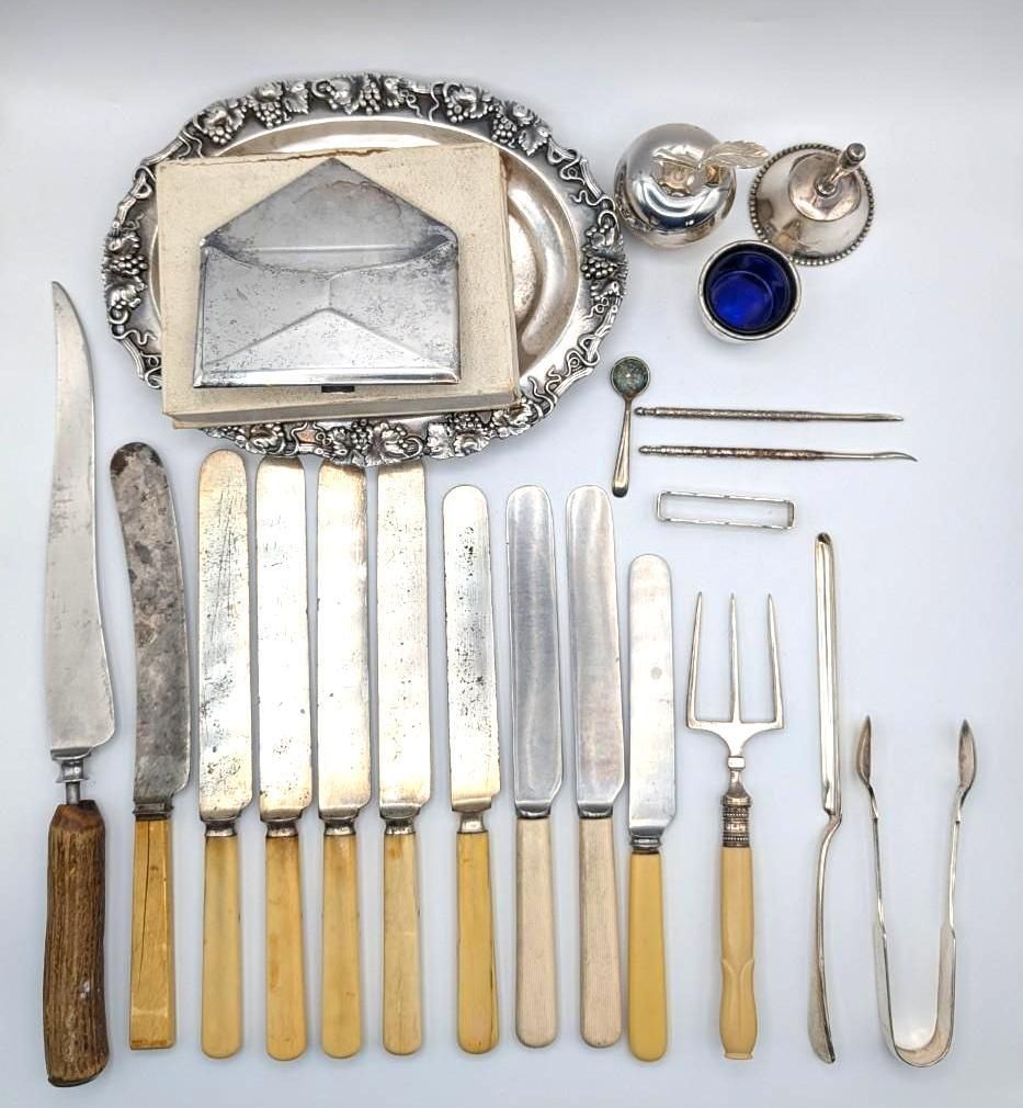 An assortment of vintage silverware, including a decorative tray, envelope-shaped case, knives, forks, and serving tools.
