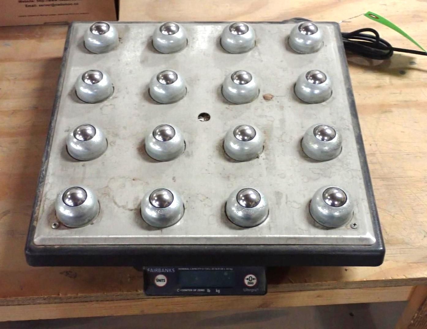 A square panel with 16 silver buttons, a small display, and a power cord.