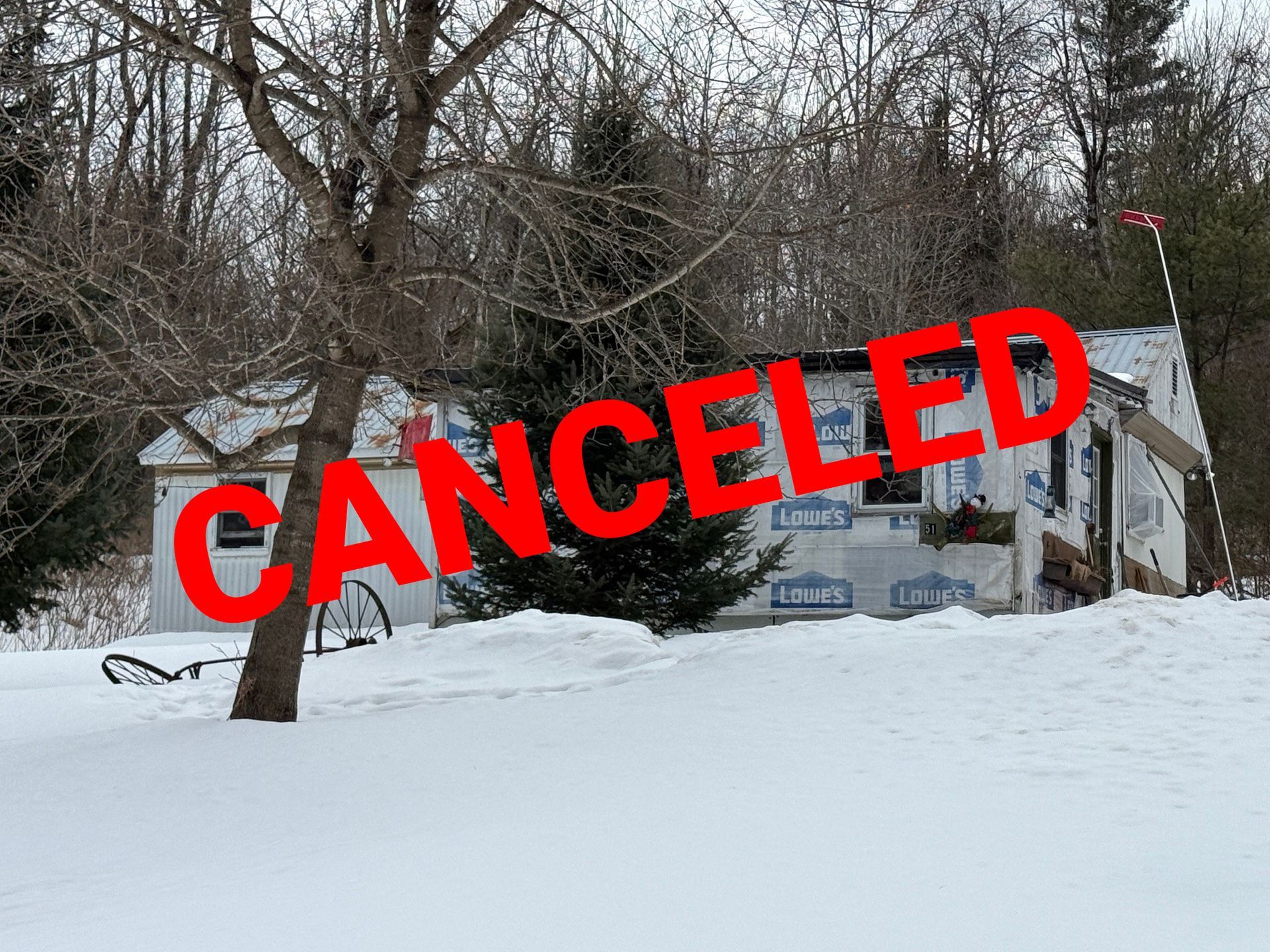 A small house sits in a snow-covered yard among trees.