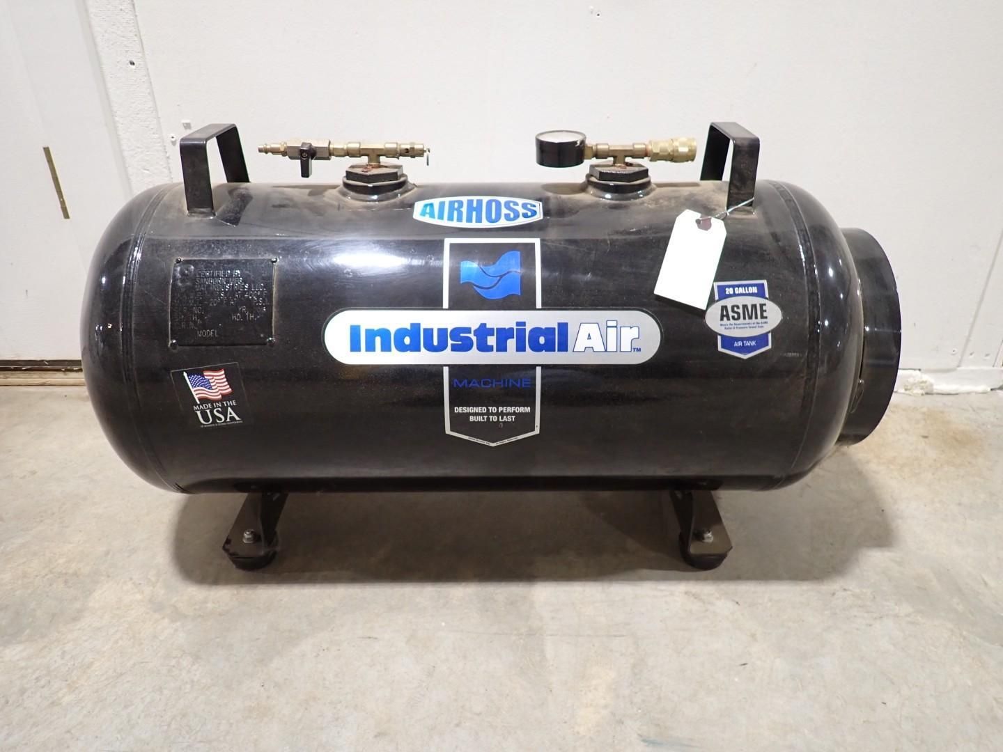 A black Industrial Air portable air compressor tank with two handles, sitting on a concrete floor.