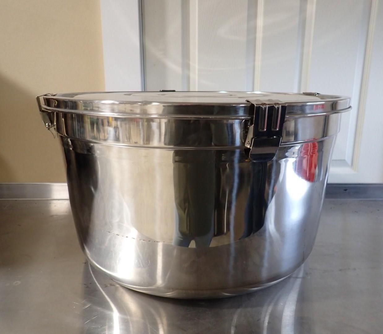 A large, polished stainless steel mixing bowl with a locking lid, sitting on a metallic countertop.
