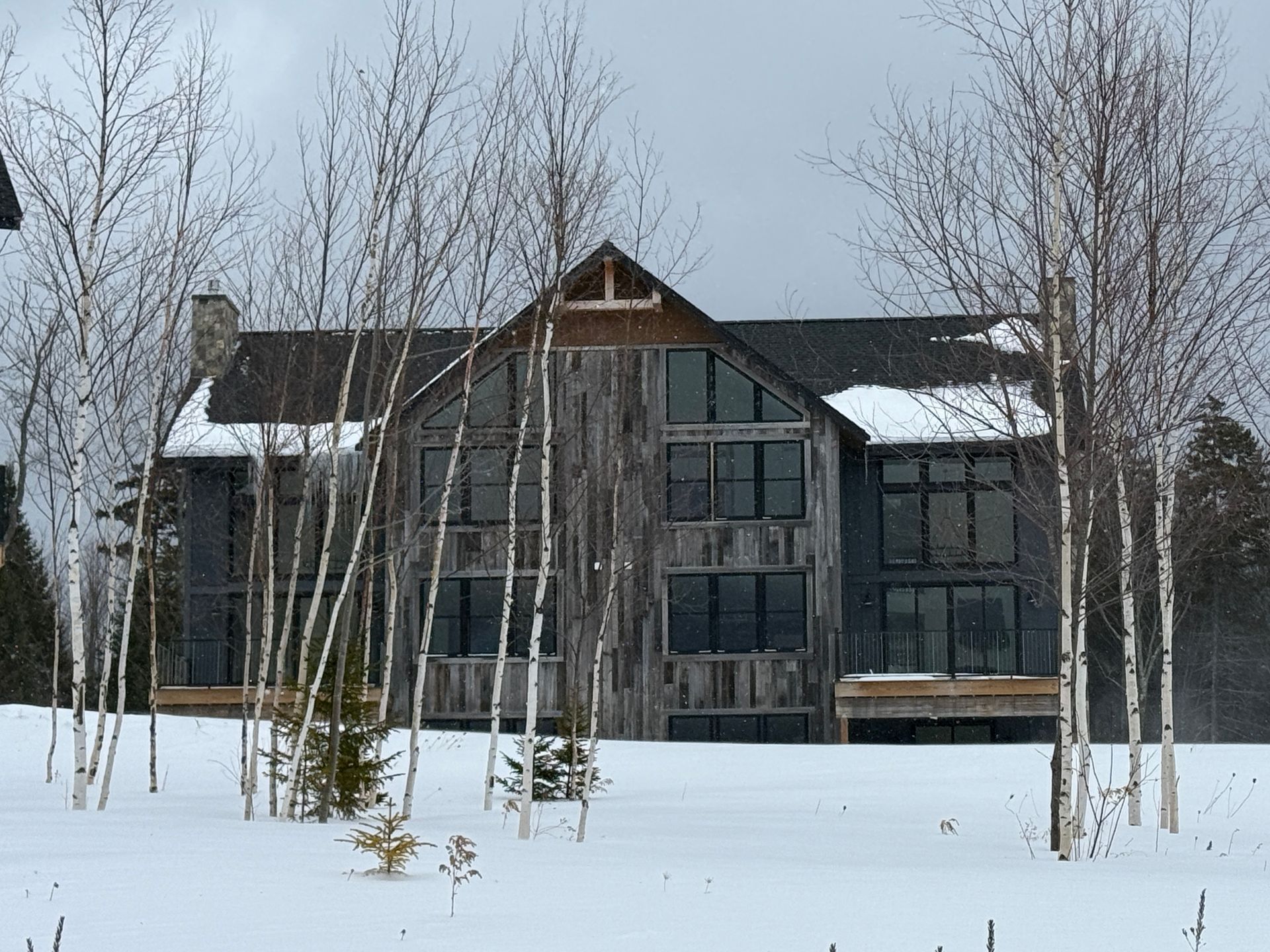 A large, weathered wooden house with tall windows. Boulder Ridge Foreclosure Property.