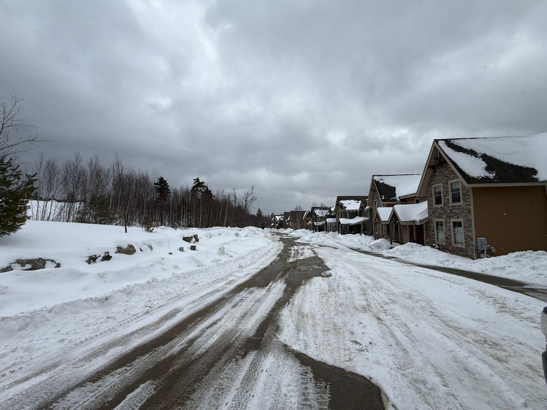 Snowy street with houses on the right, cloudy sky overhead, Boulder Ridge Foreclosure Property.