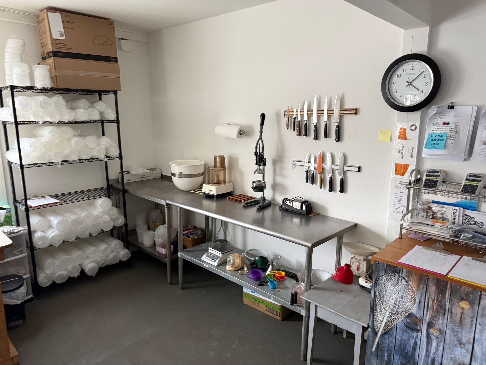 Commercial prep room with stainless steel tables, shelves of supplies