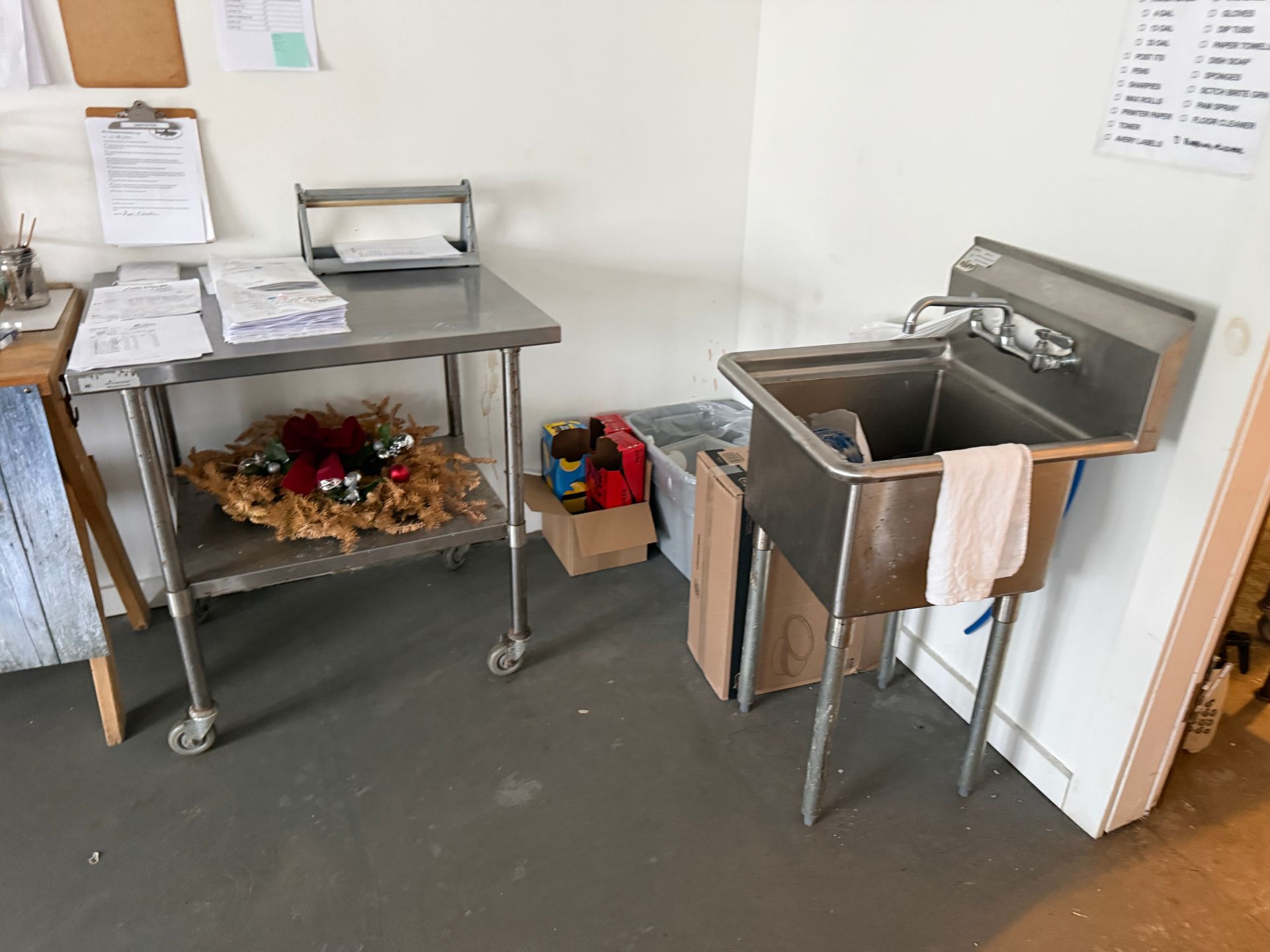 Commercial kitchen corner with stainless prep tables, sink, towels