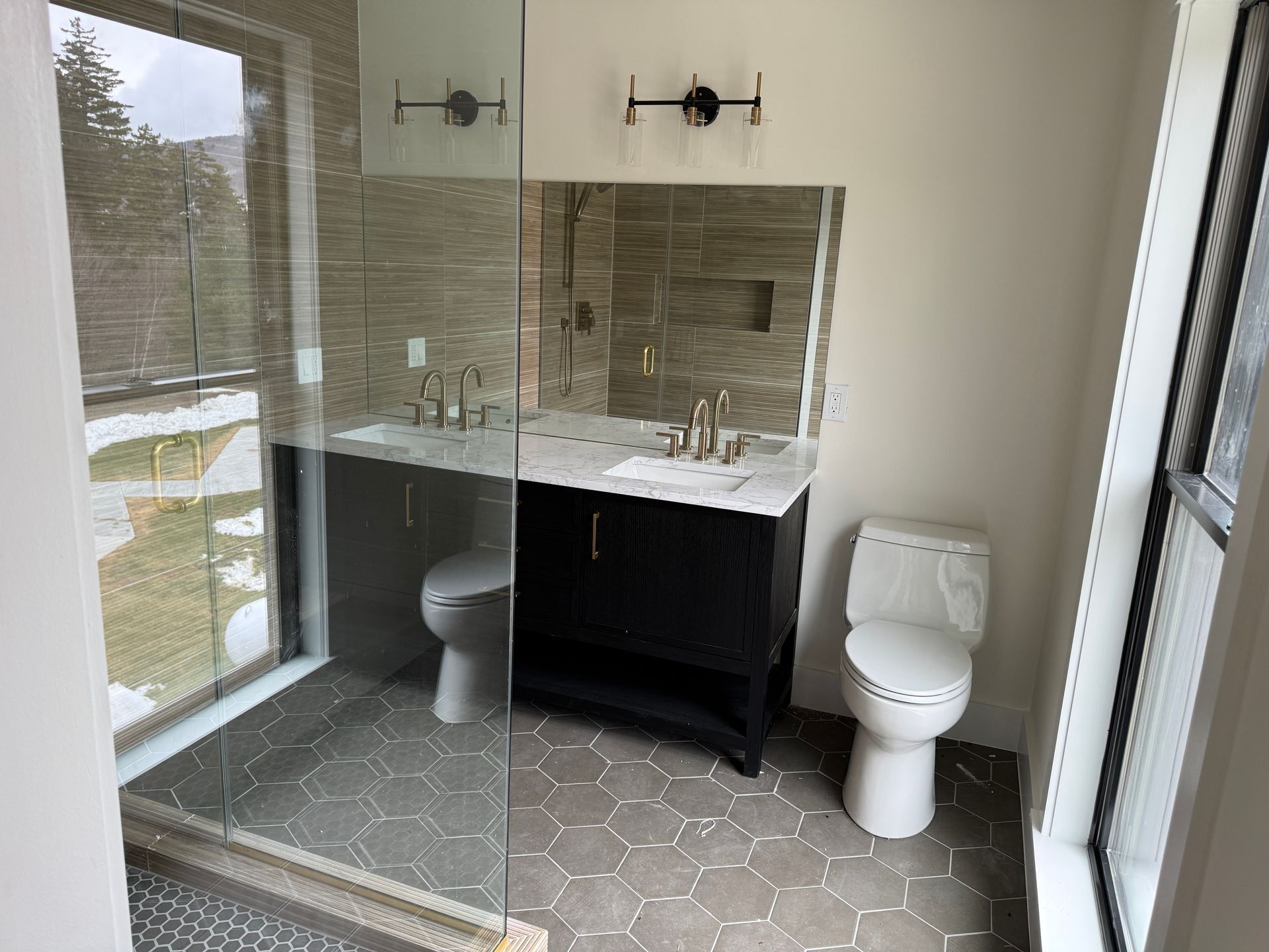 A modern bathroom with a glass-enclosed shower, a dark wood vanity with a white countertop, and a white toilet.