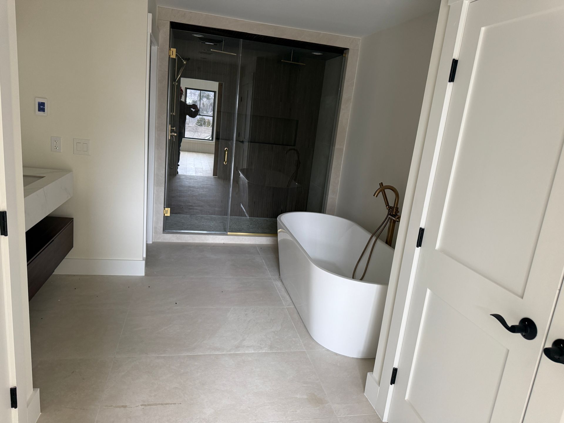 A modern bathroom featuring a white freestanding tub, a walk-in glass shower, and a minimalist vanity.