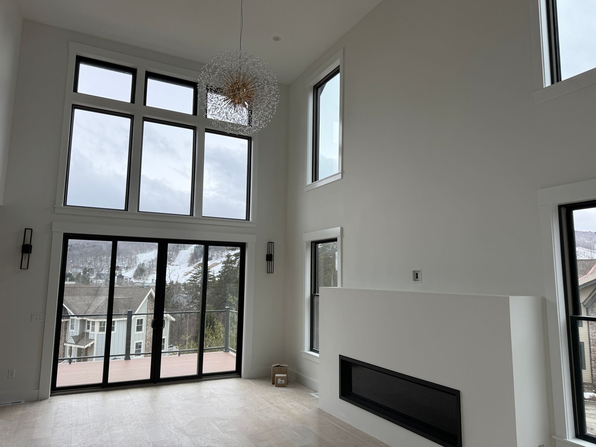 Bright living room with tall windows, a modern fireplace, and a light-colored tile floor.