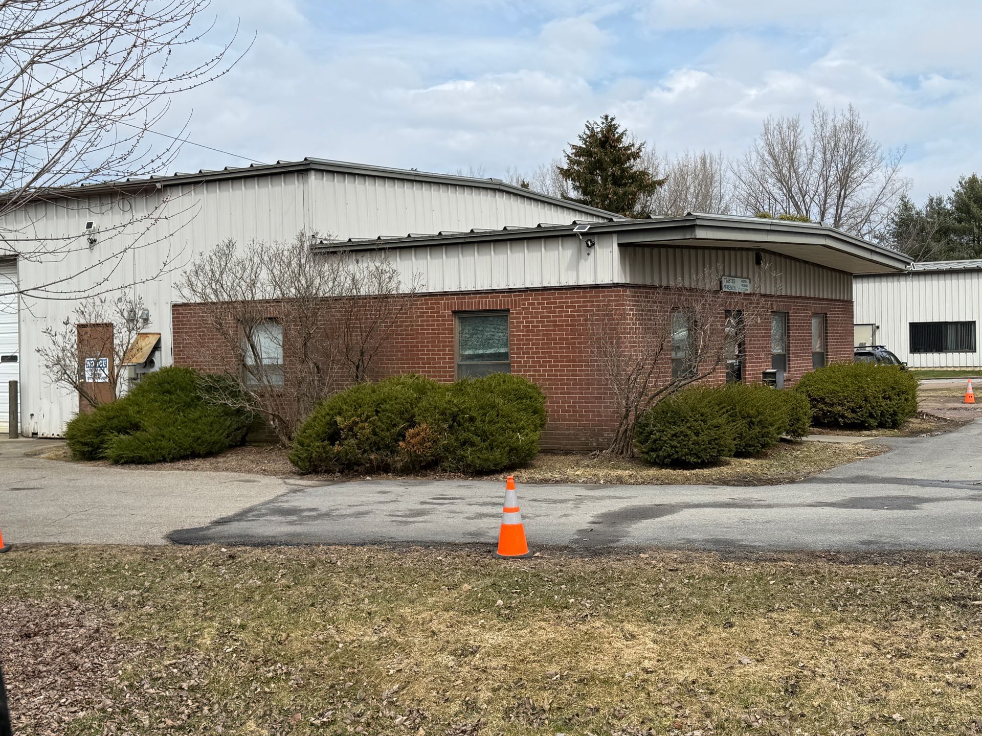 Brick industrial building with white metal roof, shrubs