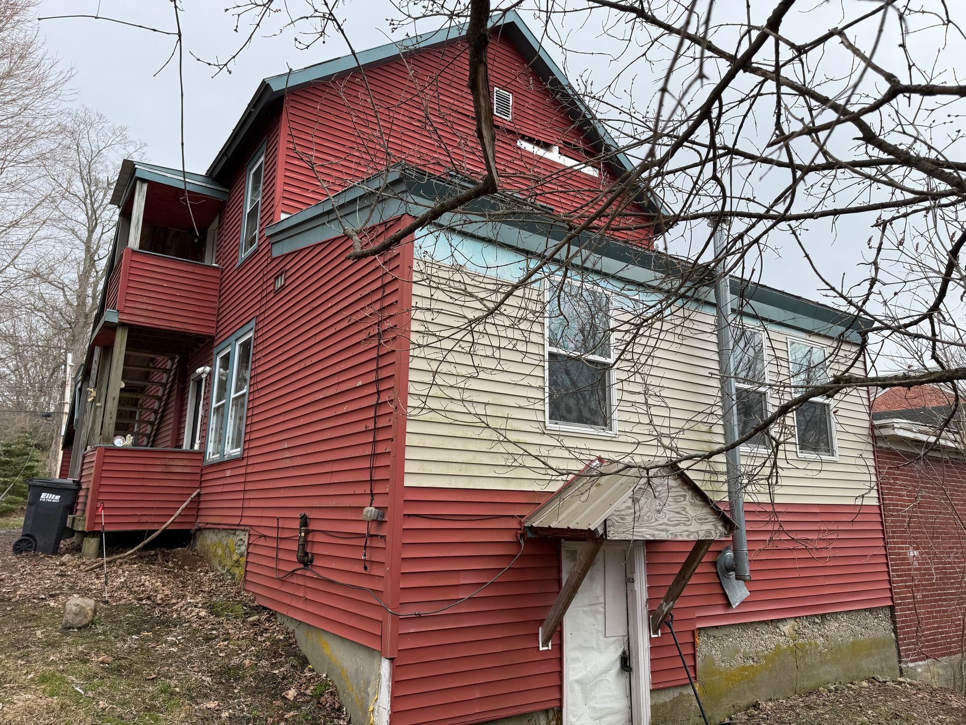 A two-story house with red and cream siding, a small exterior porch.