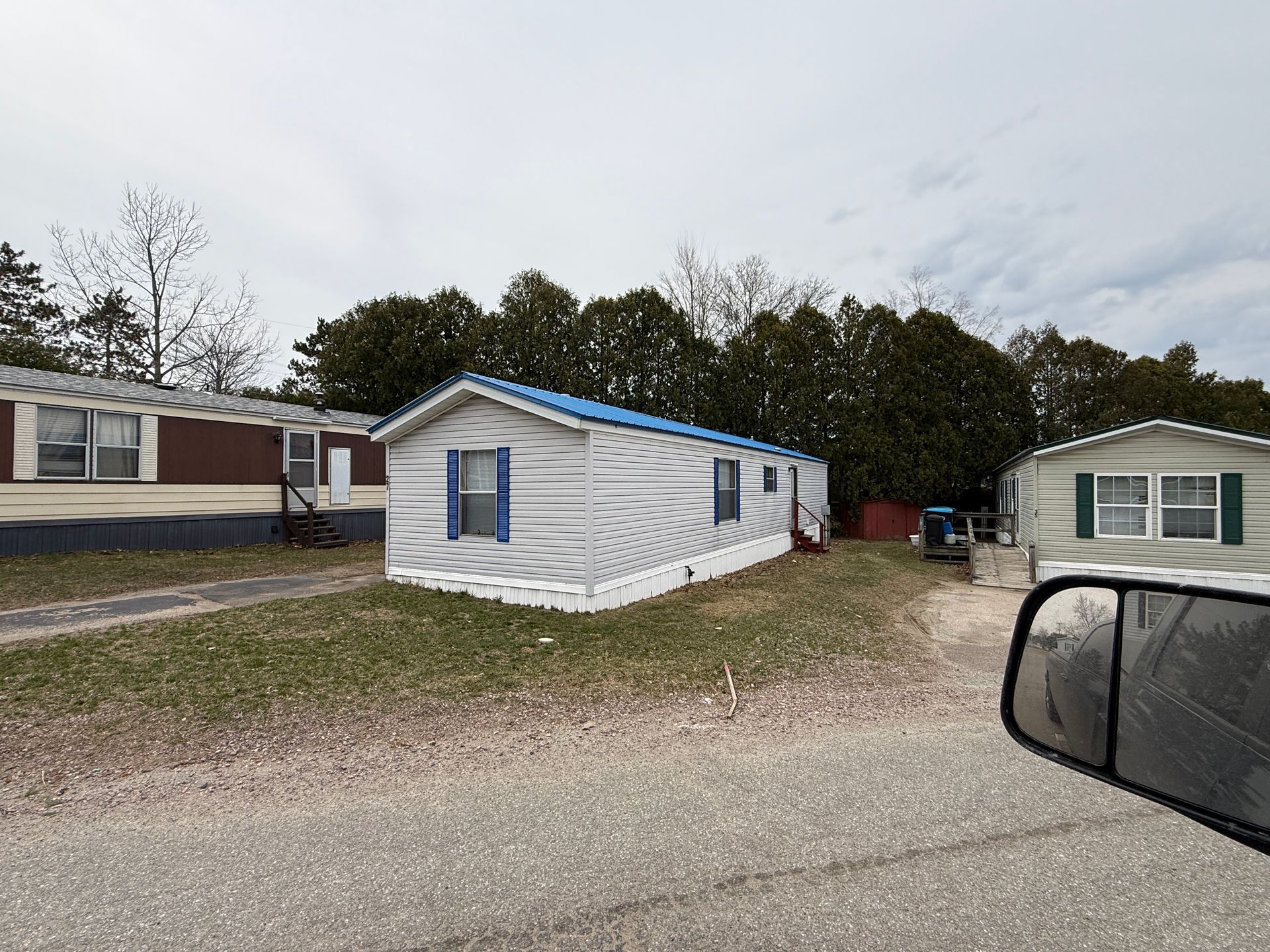 Three mobile homes sit in a row on a grassy lot.