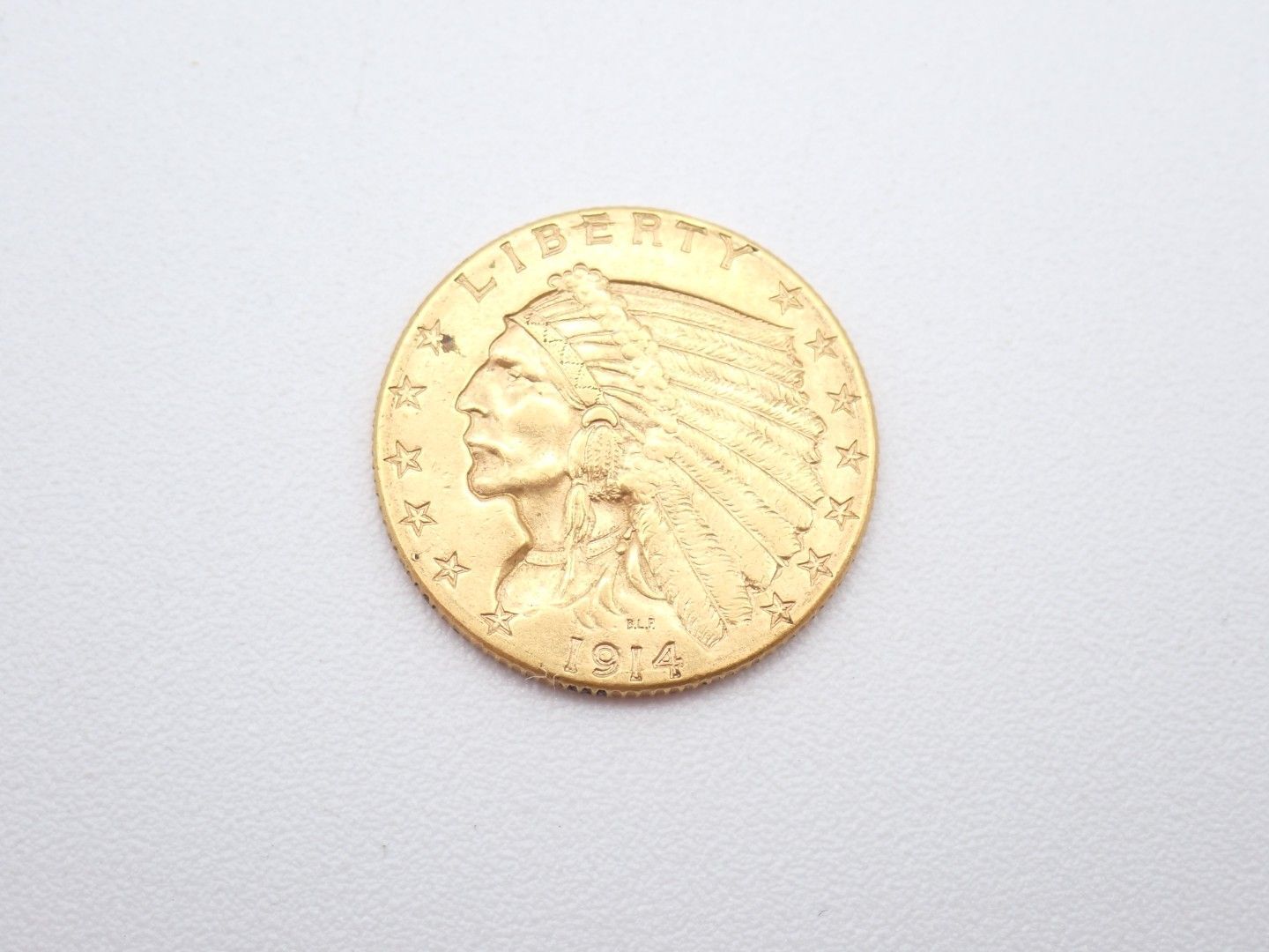 Gold coin with a Native American profile on a light gray background