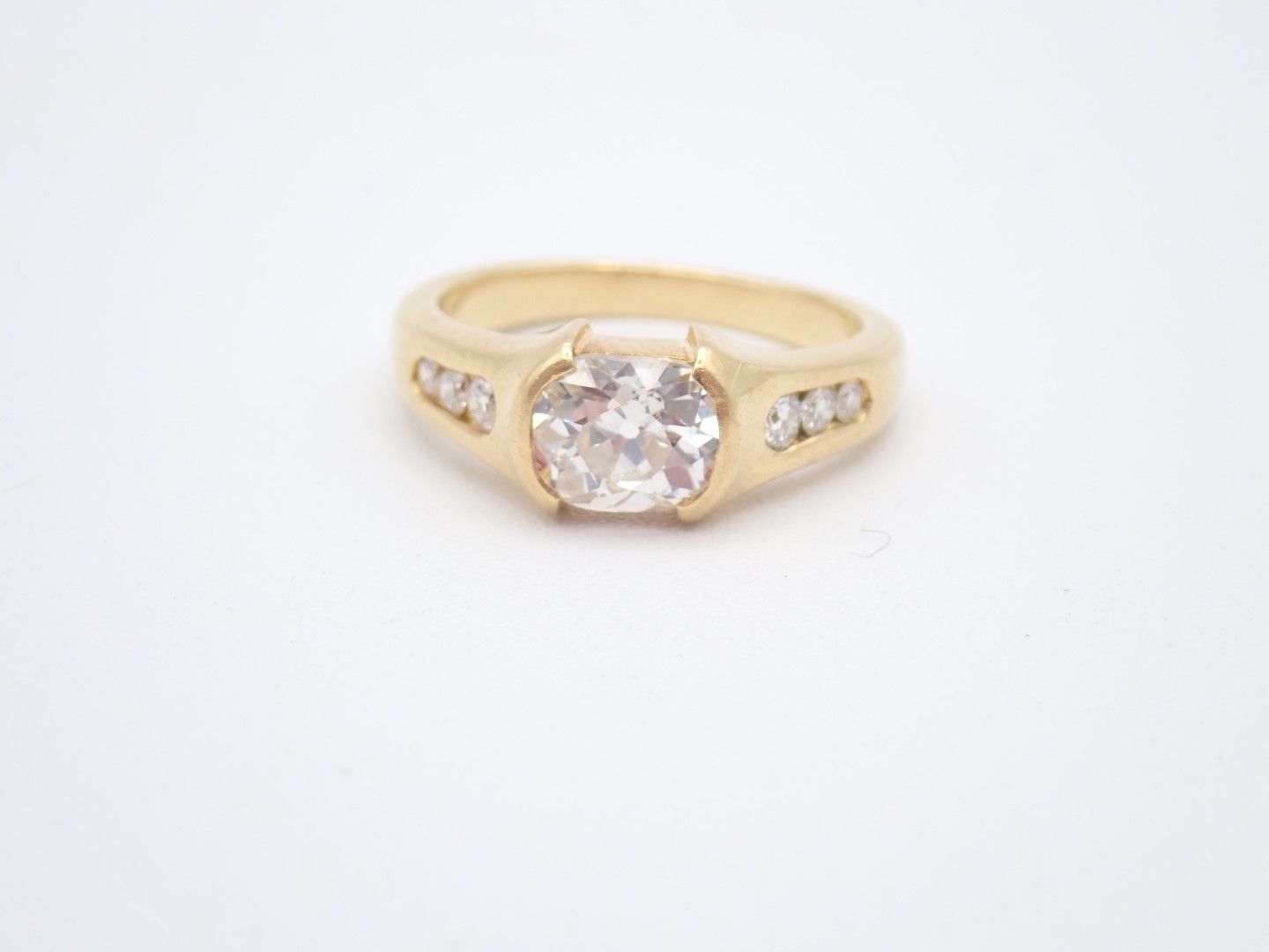 Gold ring with a large clear gemstone and small side stones on a white background
