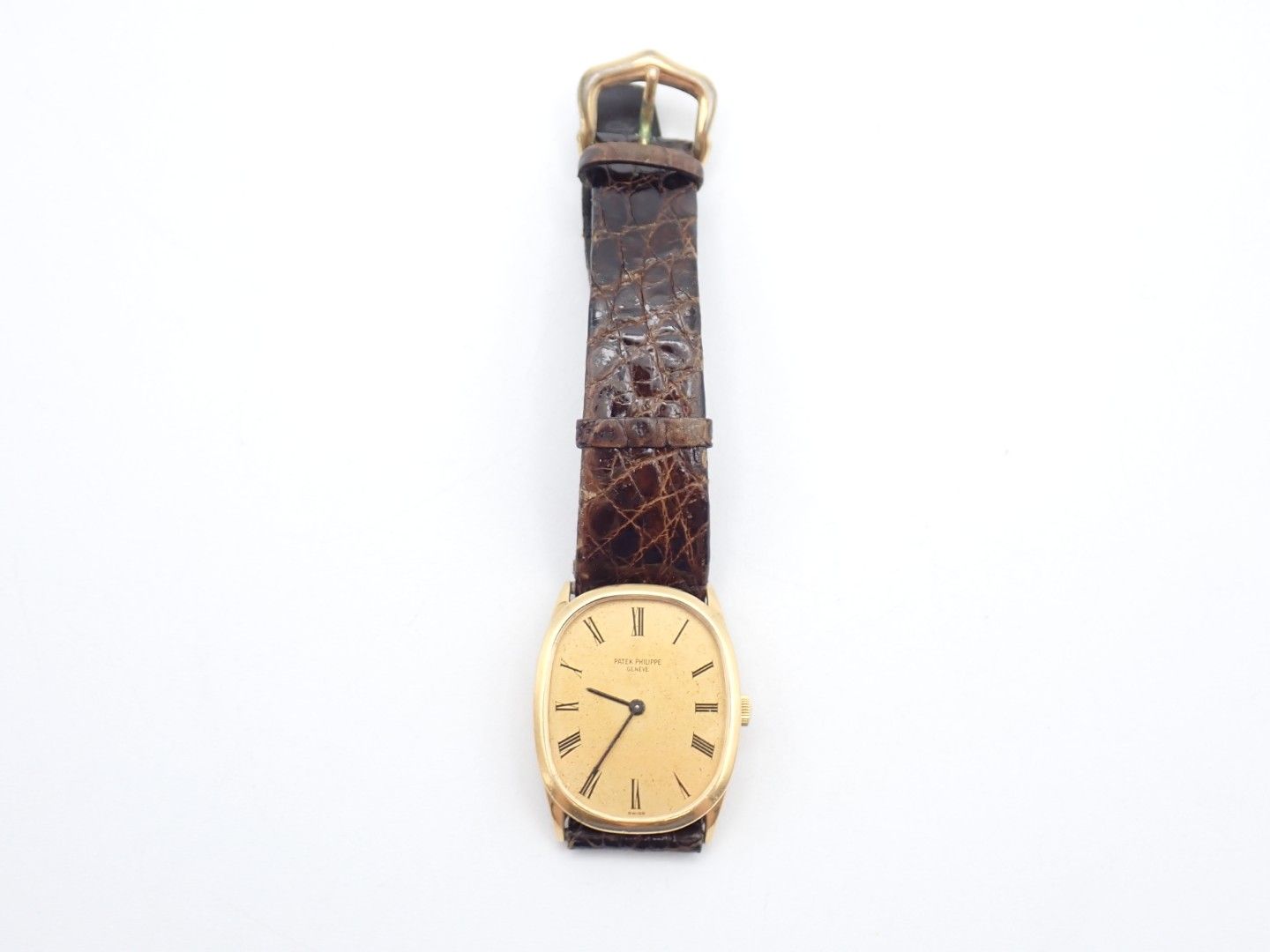 Vintage gold wristwatch with a brown leather strap on a white background