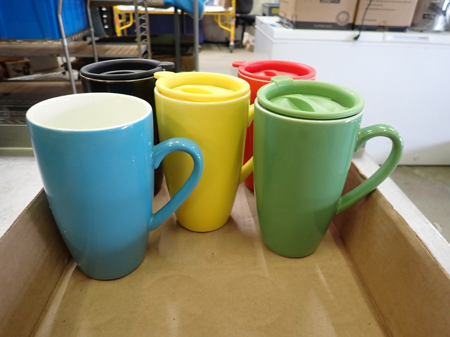 Four colorful ceramic mugs—blue, yellow, red, and green