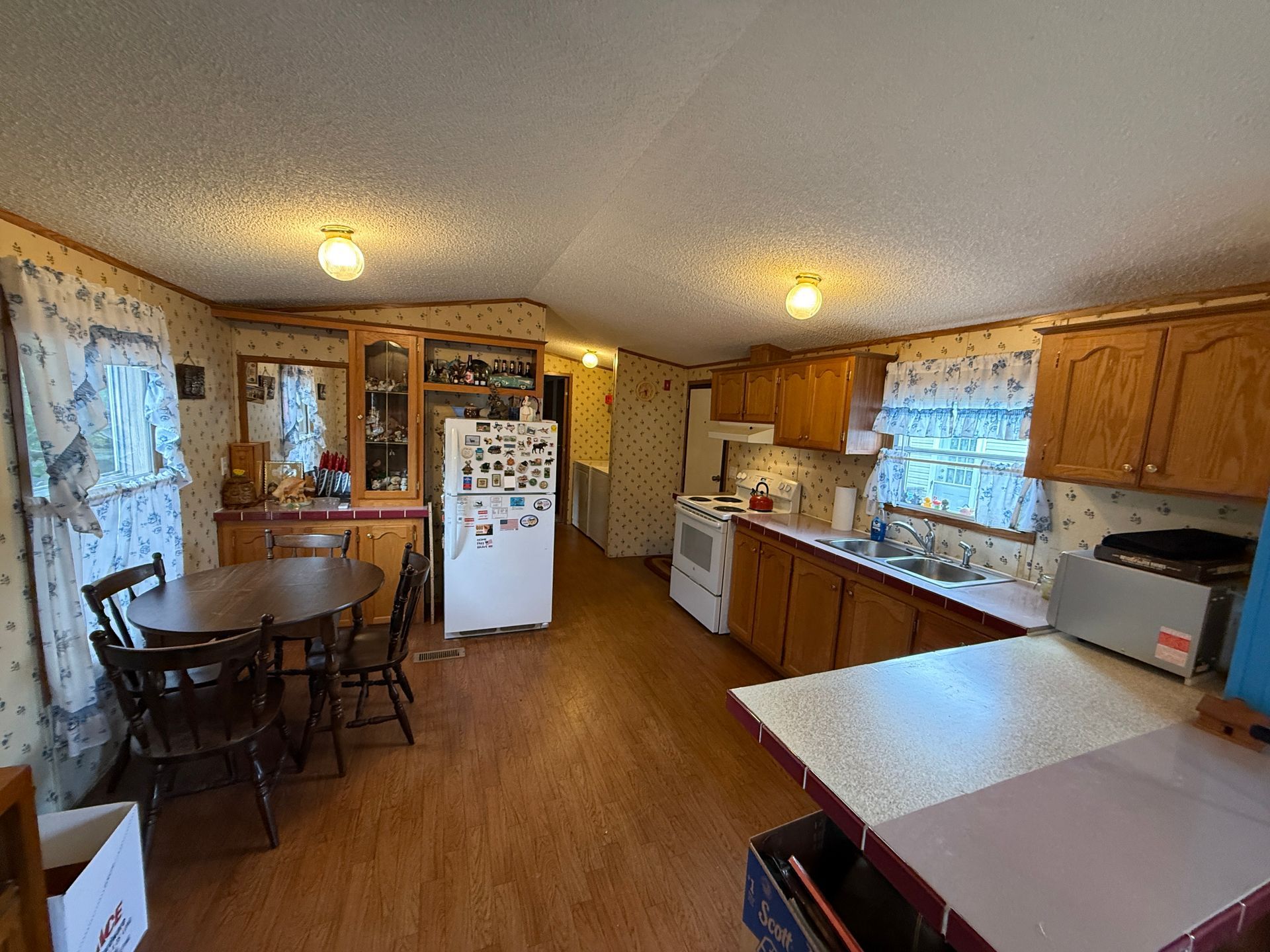 Kitchen and dining area with wooden cabinets, white appliances, and a table by the window.